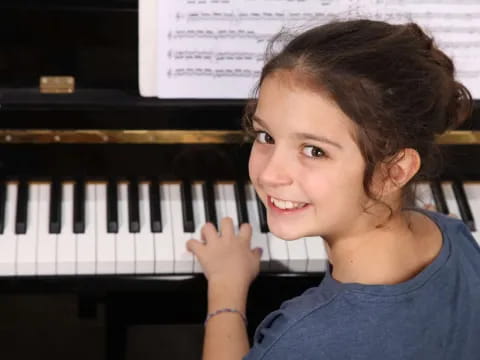 a girl smiling and holding a piano