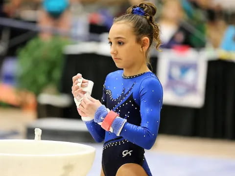 a girl wearing a blue leotard and gloves