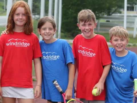 a group of kids pose for a picture with tennis rackets