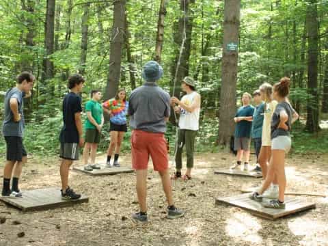 a group of people standing around a wood object in the woods