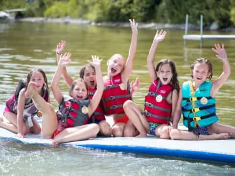a group of girls in life jackets on a raft in the water