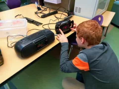 a person sitting at a desk with a camera on the hand