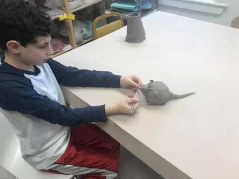 a boy sitting at a table with a small bird on it