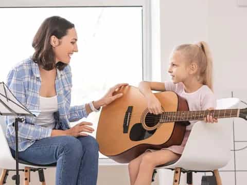 a person playing guitar to a young girl