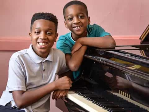 a couple of boys playing a piano