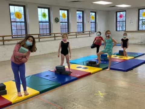 a group of kids playing on a mat in a room with windows