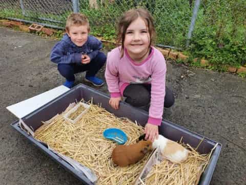 a couple of children sitting in a wheelbarrow with a snake in it