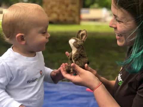 a person and a baby playing with a rabbit