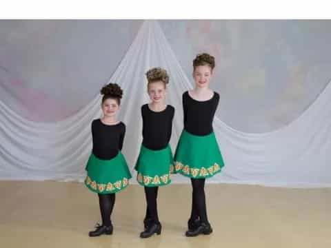 a group of women in black and green skirts