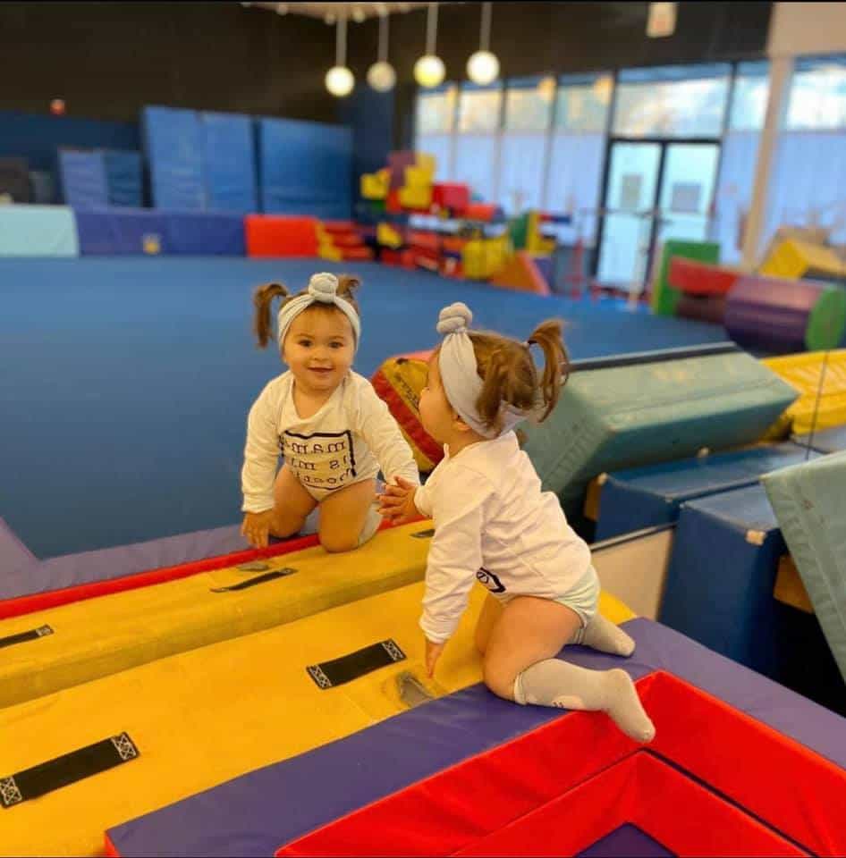 a couple of girls playing on a mat in a gym