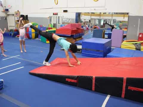 a person doing a handstand on a mat in a gym