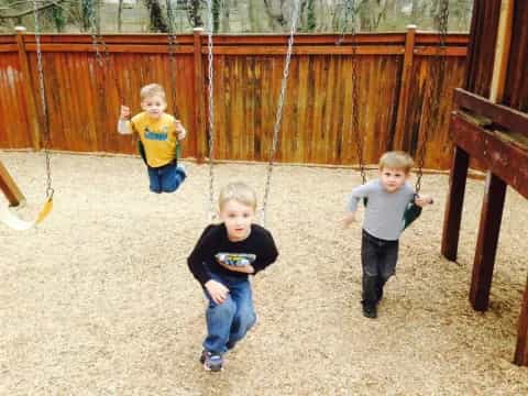 a group of children playing on a swing set