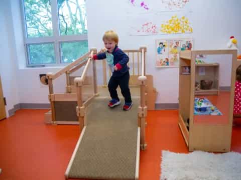 a child on a slide in a room with a window and a wood frame