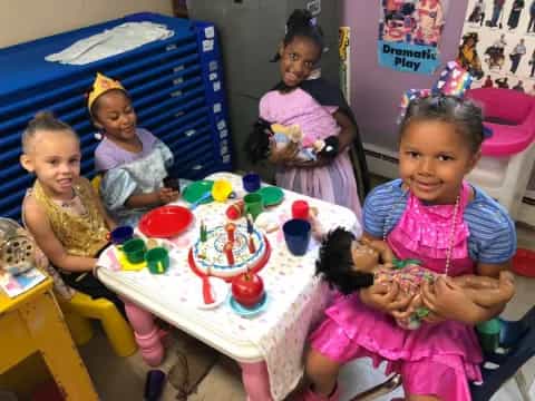 a group of children sitting at a table with a birthday cake