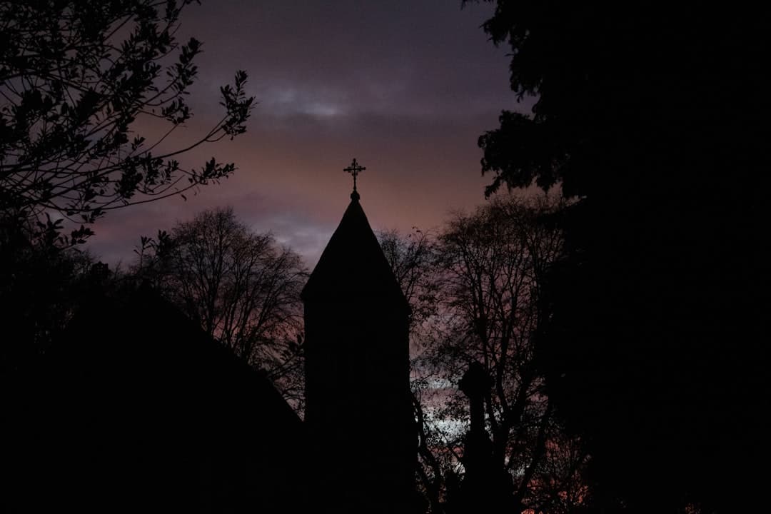 a church steeple is silhouetted against the evening sky