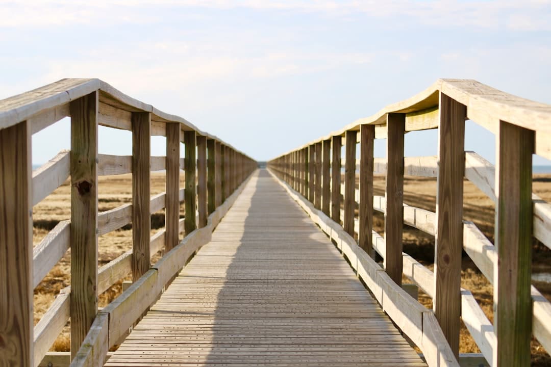 a wooden bridge over a sandy beach on a sunny day